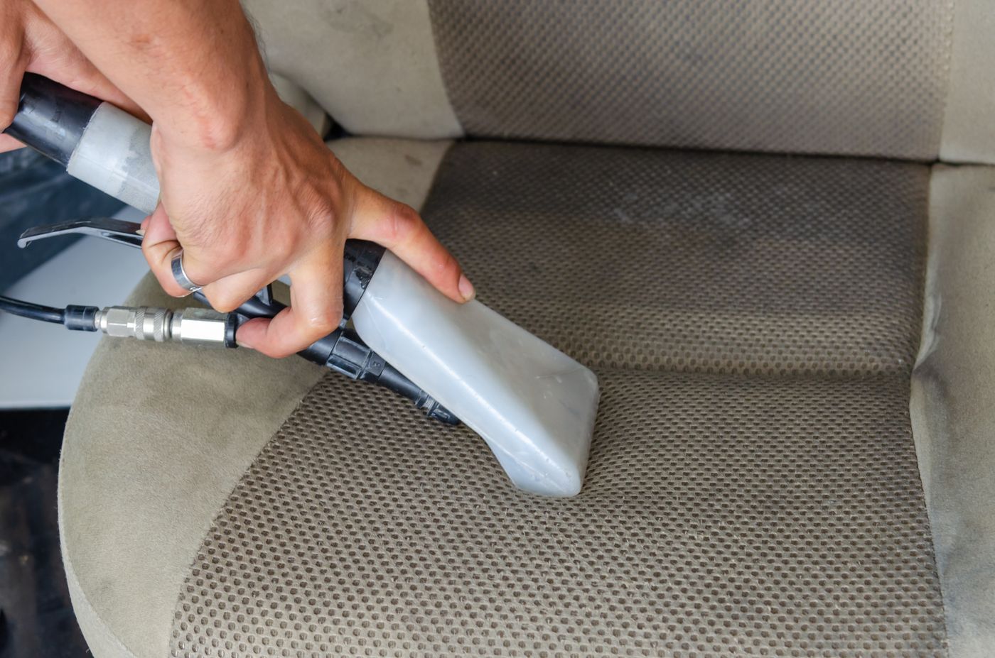 A car seat being deep cleaned with a professional steam extraction tool