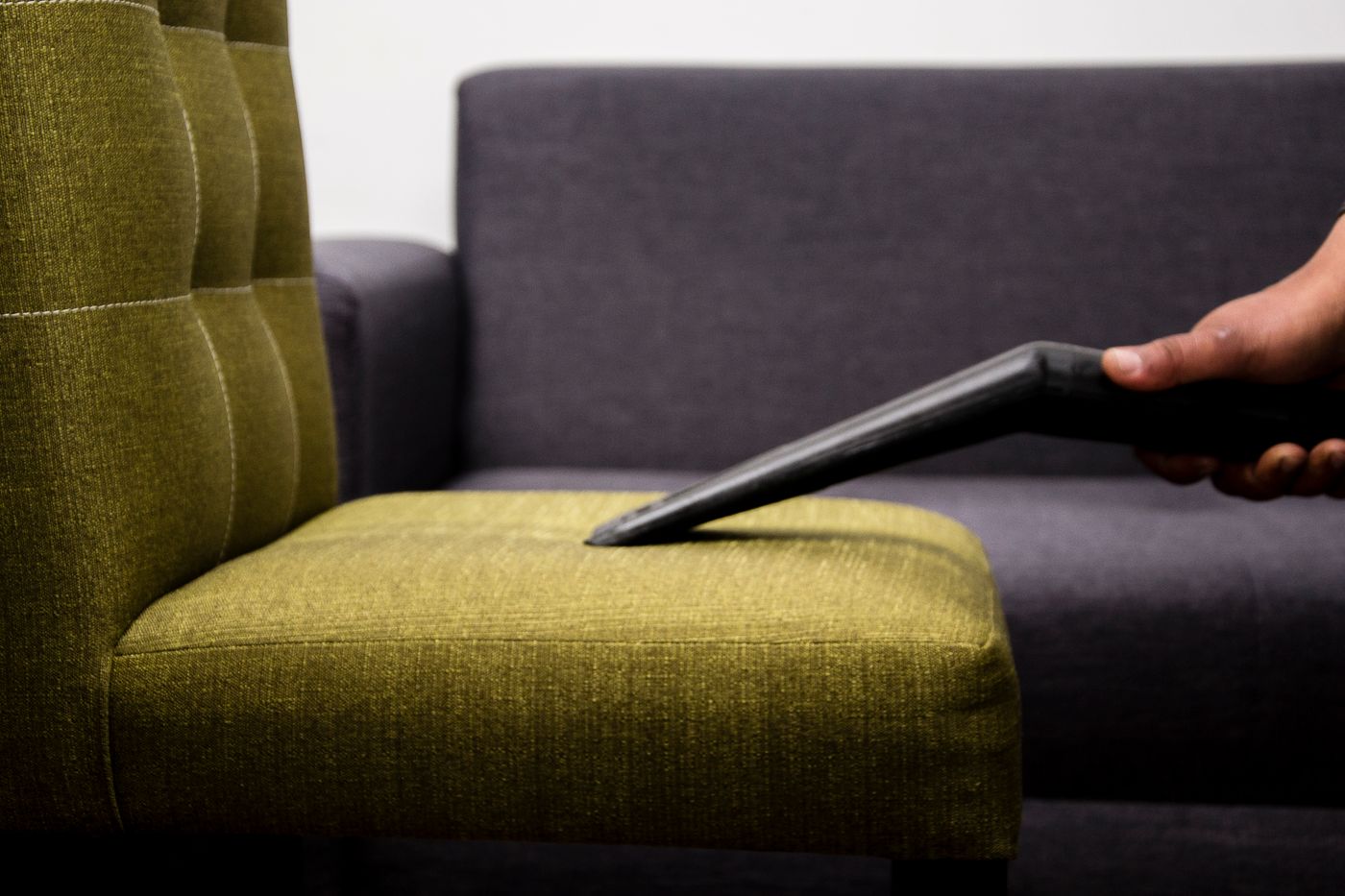 A fabric armchair being deep cleaned with a professional upholstery tool